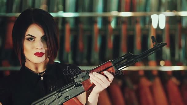 Tiukka tyttö poseeraa pitäen Kalashnikov kivääri
. - Materiaali, video