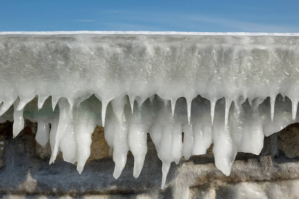 Fragment van een bevroren golfbreker muur met ijspegels  - Foto, afbeelding