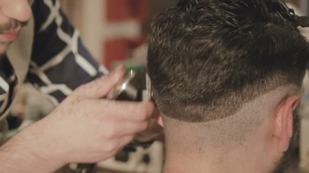 mens hairstyling and haircutting with hair clipper in a barber shop or hair salon - Filmati, video