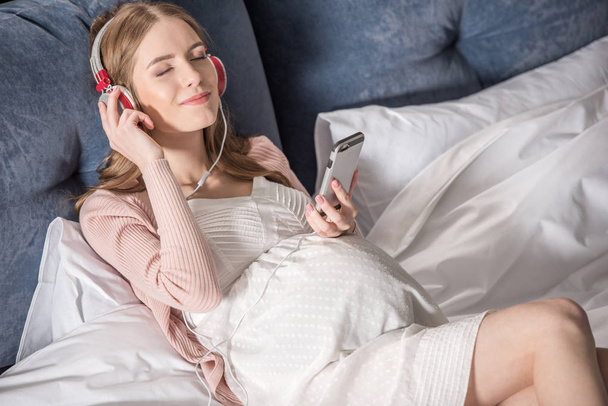 terhes nő fülhallgatóval - Fotó, kép
