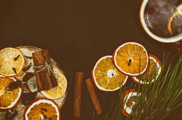 φλιτζάνι καυτό τσάι με φέτες από λεμόνι και πορτοκάλι σε ένα μαύρο ξύλινο - Φωτογραφία, εικόνα