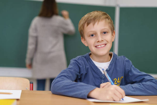 Happy little boy doing class work in school - 写真・画像