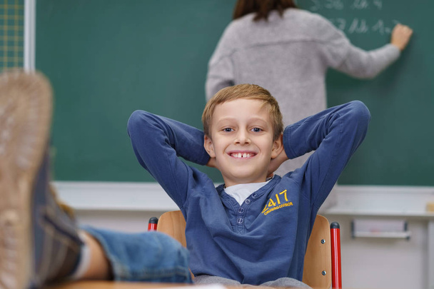 Cute young boy with his feet up in class - Photo, image