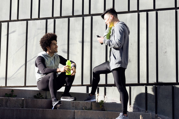 Two fit and sporty young men relaxing and stretching after work  - Фото, изображение