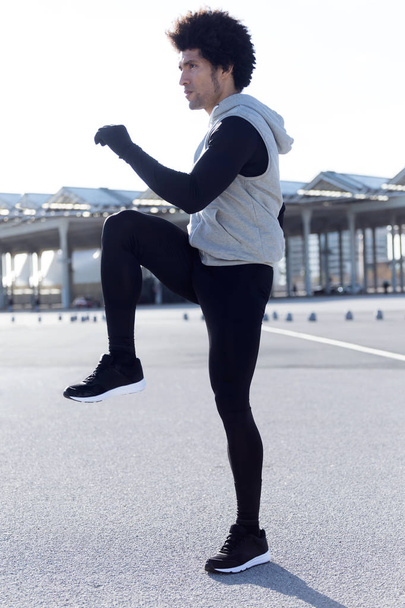 Fit and sporty young man doing stretching in city. - Фото, изображение