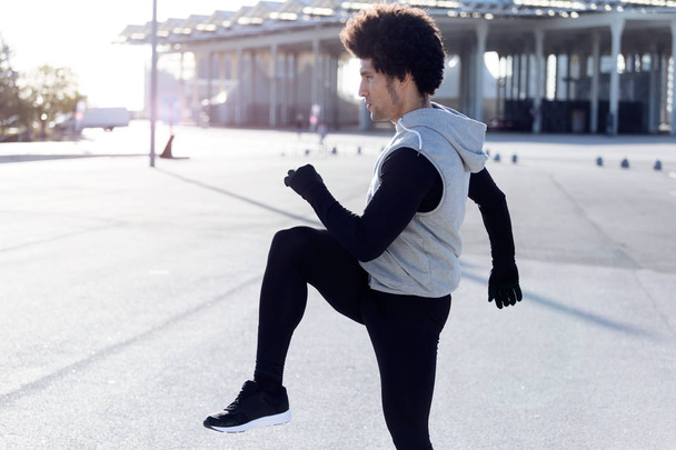 Fit and sporty young man doing stretching in city. - Foto, Bild