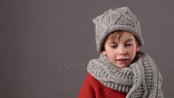 smiling young boy wearing warm scarf and hat, copy space - Кадры, видео