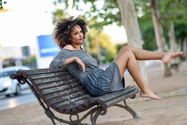 Joven mujer negra con peinado afro sonriendo en el fondo urbano
 - Foto, imagen