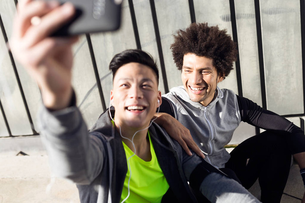 Due uomini in forma e sportivo youn utilizzando il telefono cellulare in città
. - Foto, immagini
