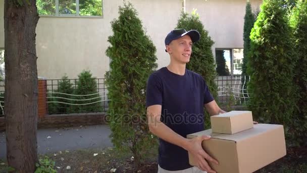 Voetgangers Courier hebben grote bundel in de Hand met lachende op achtergrond van bomen en huis overdag buitenshuis. - Video