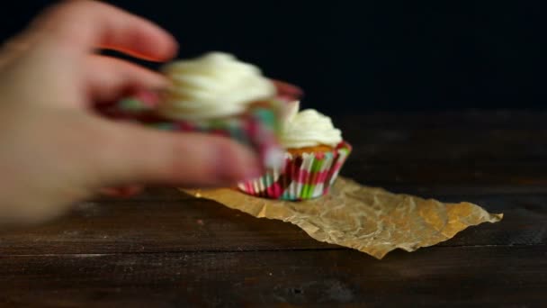Muffiny s dort krémem na pečícím papírem. Ruce položte košíček na stůl - Záběry, video