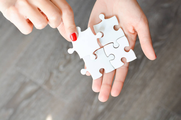 Woman hand fitting the right piece of puzzle suggesting business  networking concept - 写真・画像