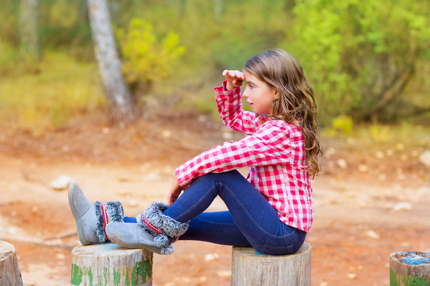 Kid girl sitting in forest trunk looking far away - Photo, Image