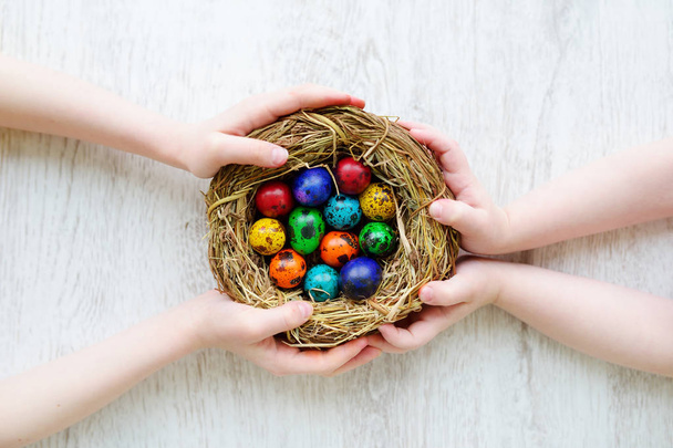 Two children holding nest with  Easter eggs - Φωτογραφία, εικόνα