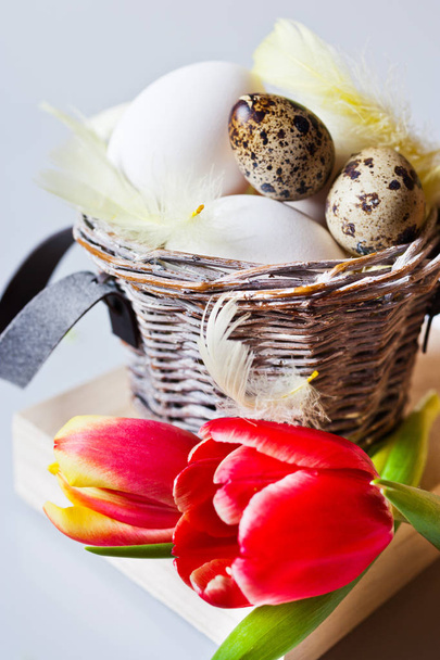 Traditional Czech easter decoration - white eggs with tulip flowers in the basket nest, quail eggs and feather. Spring easter holiday arrangement. - Photo, Image