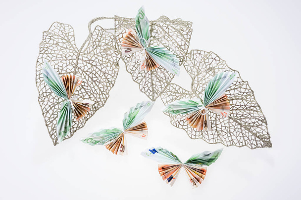 Eurobiljetten in de vorm van vlinders op decoratieve glinsterende blad - Foto, afbeelding