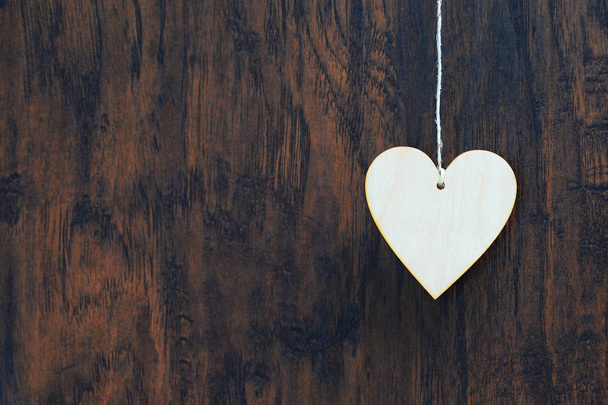 Plywood heart hanging on the clothesline. On old wood background - Fotografie, Obrázek