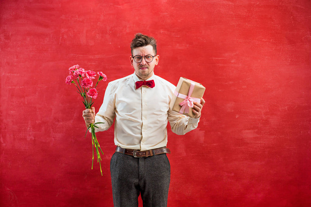 Young funny man with flowers and gift - 写真・画像