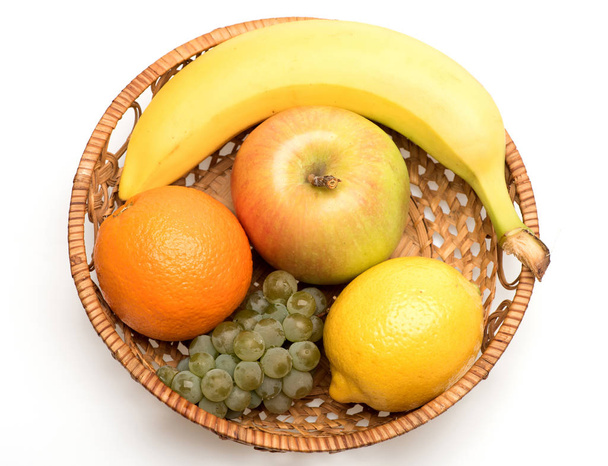 banán, citrom, alma, szőlő és narancslé szalmakosárban - Fotó, kép