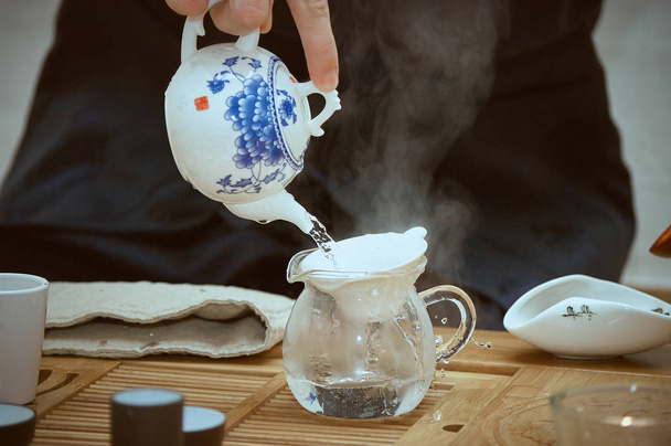 Mestari kaataa teetä kiinalaisessa teetilaisuudessa
 - Valokuva, kuva