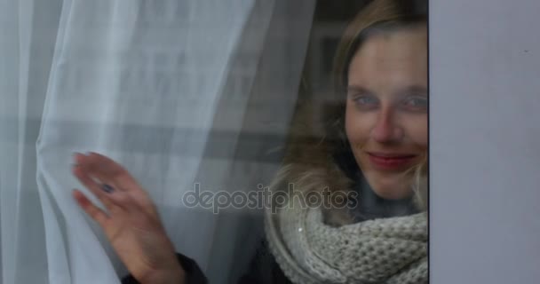 Mulher jovem cortinas abertas e olhando através da janela com sorriso
 - Filmagem, Vídeo