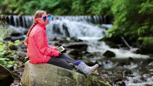Dívka sedí u malé řeky - Záběry, video