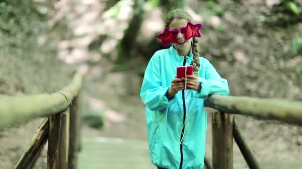 Mooi meisje met smartphone staat op brug  - Video