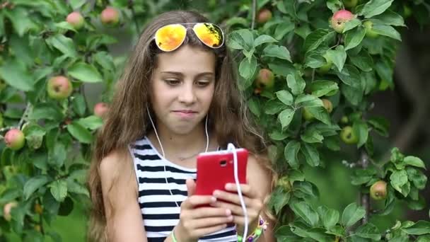 Krásná dívka mluví o červené smartphone - Záběry, video