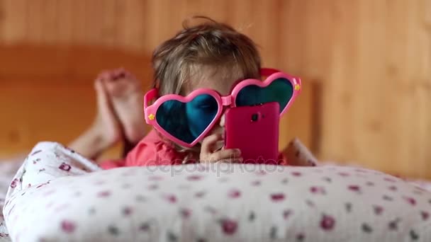 dívka s smartphone leží na posteli - Záběry, video