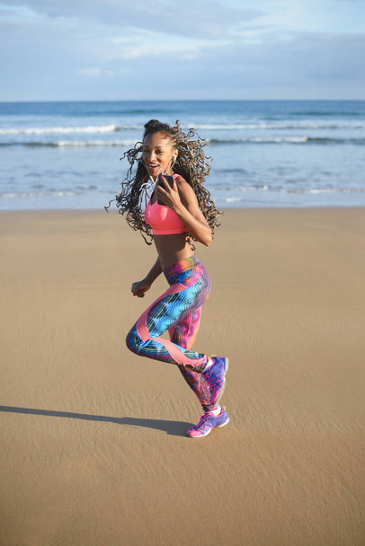 Fit black woman running and exercising on the beach - Фото, зображення