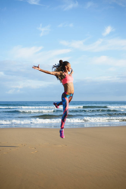 Urheilullinen musta nainen tanssii ja treenaa rannalla
 - Valokuva, kuva