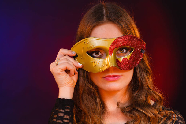 Closeup woman face with carnival golden red mask on dark - Fotó, kép