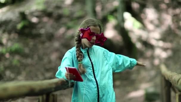 Chica con soportes de teléfonos inteligentes en puente de madera
 - Metraje, vídeo