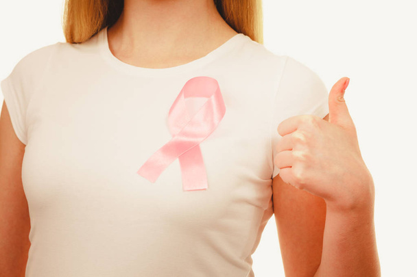 Closeup pink cancer ribbon on woman chest  - 写真・画像