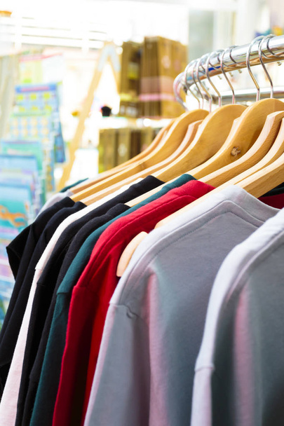 Surtido de camisas colgando de perchas en una barandilla circular de metal en una tienda o boutique en una vista cercana de los hombros de las prendas - Foto, imagen