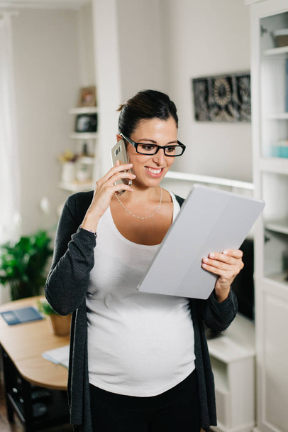 Pregnant woman working at home with tablet pc and smartphone - Фото, изображение