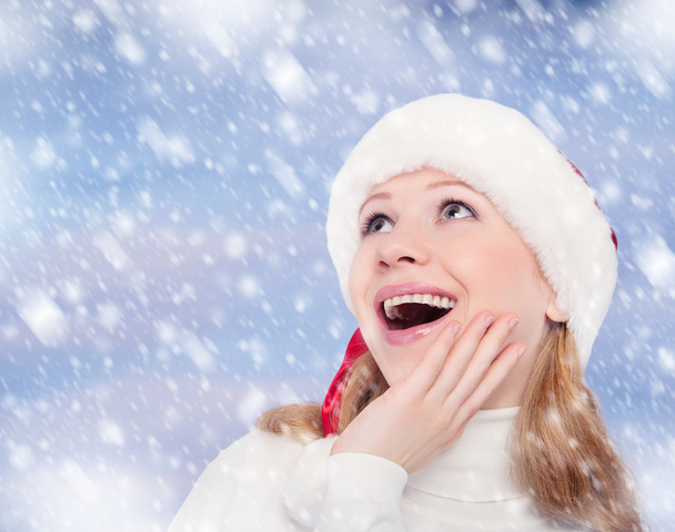 Happy funny girl in a Christmas hat on winter background - Foto, Imagem