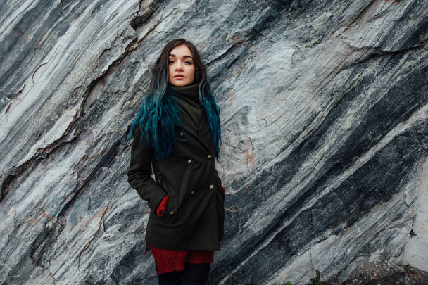 Portrait of a beautiful hipster girl on the background  the rocky cliffs. Dyed hair, blue, long. - Fotografie, Obrázek