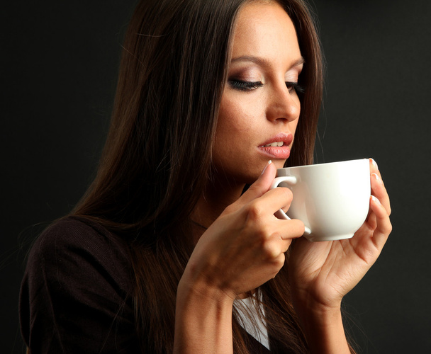 beautiful young woman with cup of coffee, on brown background - Фото, изображение