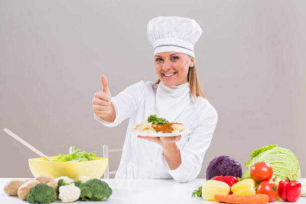 Female chef showing prepared meal and thumb up - Фото, изображение