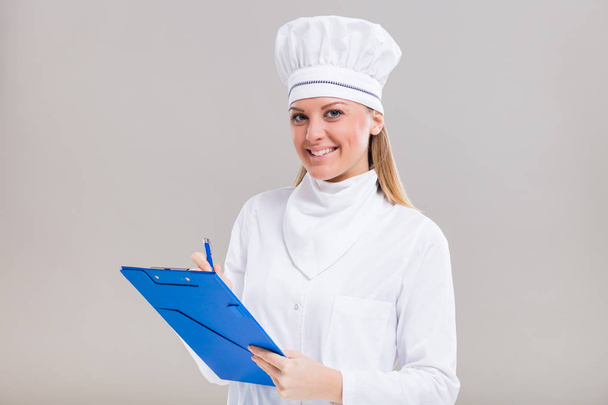 Female chef writing recipe in her cookbook - Foto, imagen