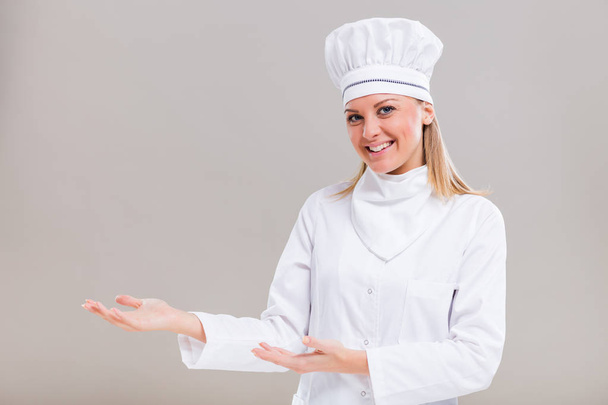 Female chef showing welcome gesture - Foto, imagen