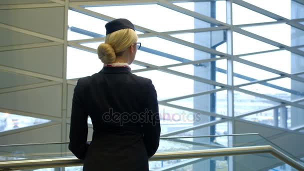 Stewardess met een bril op haar gezicht kijken uit het raam in het city. - Video
