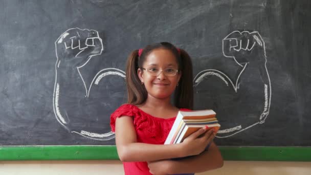 hispanisches Mädchen hält Bücher im Klassenzimmer und lächelt - Filmmaterial, Video
