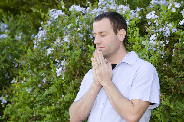 Homem rezando com as mãos juntas e os olhos fechados
. - Foto, Imagem