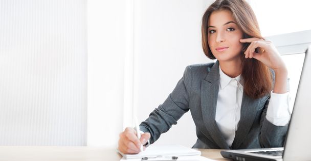 Beautiful young business woman sitting relaxed at her office and - Фото, зображення