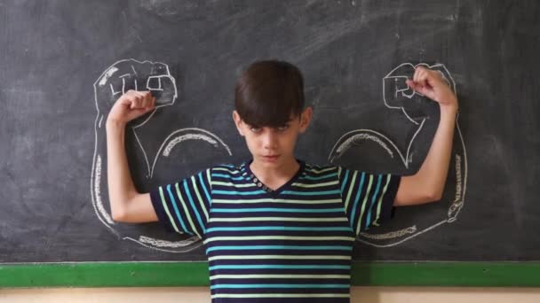 Criança masculina forte mostrando músculos na sala de aula na aula
 - Filmagem, Vídeo