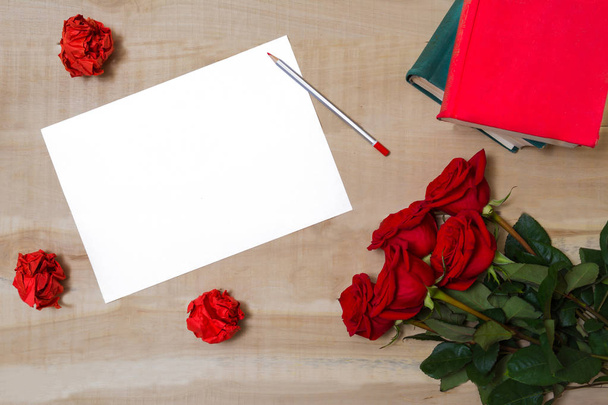 white sheet of paper lying on a wooden table with a bouquet of r - Fotografie, Obrázek