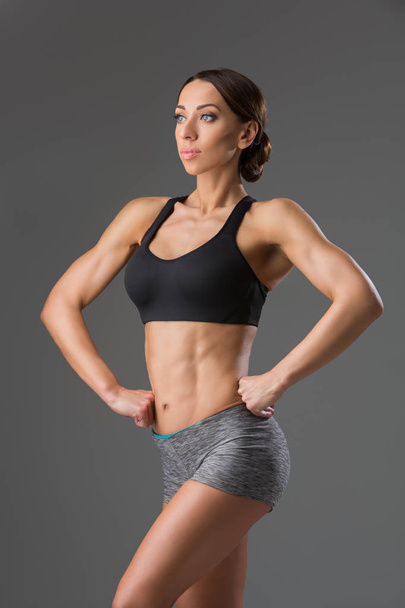 sexy woman in sport bra and panties holding sport bottle and looking at  camera isolated on grey Stock Photo by LightFieldStudios