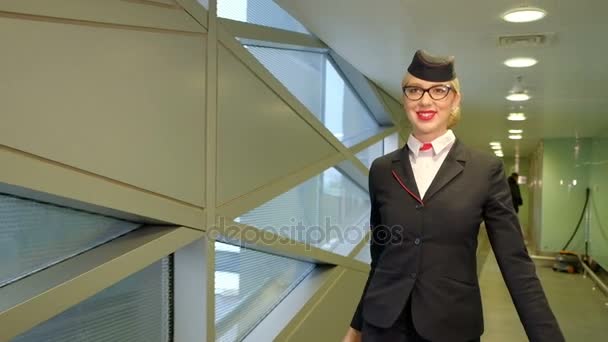 Blond letuška chodí chodbou terminálu na letišti uvnitř - Záběry, video